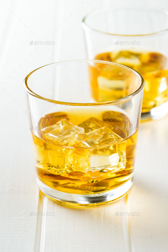 Glass of alcoholic drink with ice cubes on white table. Stock Photo by jirkaejc