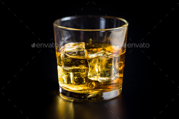 Glass of alcoholic drink with ice cubes on black table. Stock Photo by jirkaejc