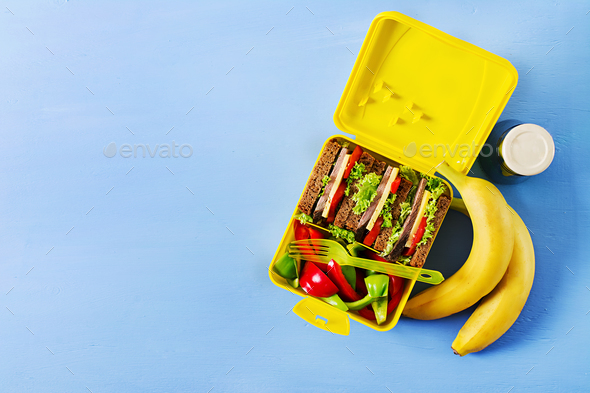 School lunch box with sandwich, vegetables, water, and fruits on