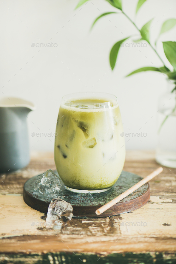 Iced matcha latte drink, white wall at background, vertical composition - Stock Photo - Images