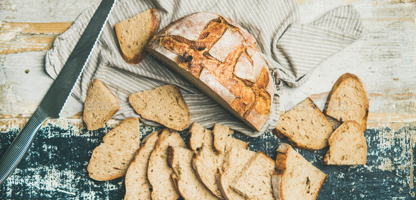 Sourdough wheat bread cut in slices on table, wide composition - Stock Photo - Images
