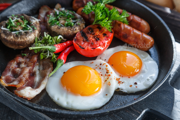 English Breakfast with fried eggs, sausages, bacon, mushrooms, jam and orange juice, copyspace Stock Photo by fazeful