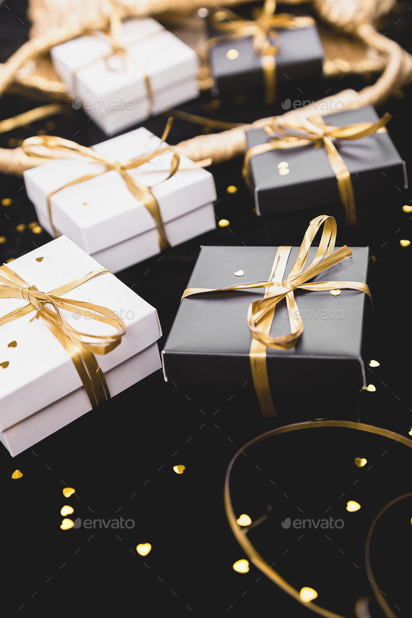 Black and white gift boxes with gold ribbon on shine background. Stock Photo by bondarillia