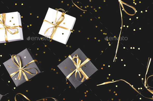 Black and white gift boxes with gold ribbon on shine background. Stock Photo by bondarillia