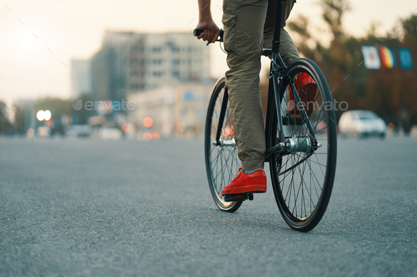 Closeup of casual man legs riding classic bike on city road Stock Photo by arthurhidden