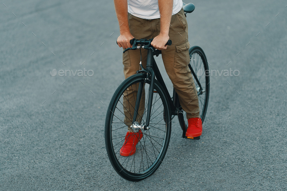 Closeup of casual man legs riding classic bike on city road Stock Photo by arthurhidden