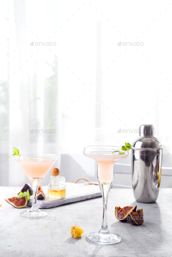 Bellini cocktail with peach and figs, honey on light background over windows, copy space Stock Photo by lyulkamazur