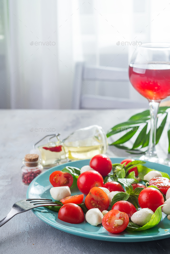Caprese salad. Healthy meal with cherry tomatoes, mozzarella balls, spices, fresh rocket - Stock Photo - Images