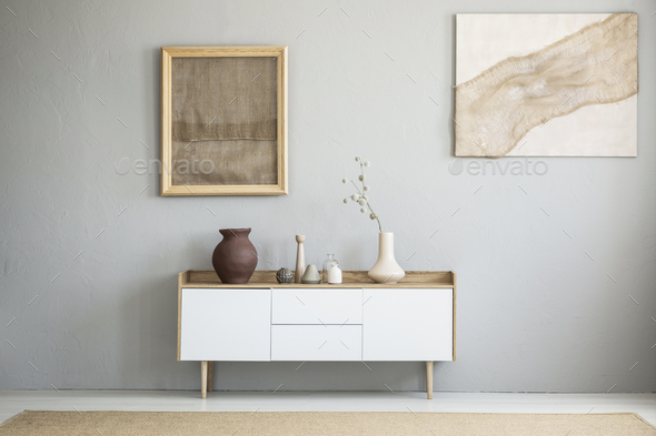 Front view of burlap artworks on a light gray wall above a woode - Stock Photo - Images