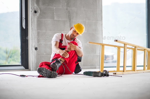 An accident of a man worker at the construction site. Stock Photo by halfpoint