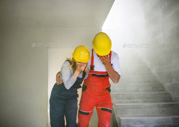 Woman and man workers suffocating at the construction site. Stock Photo by halfpoint