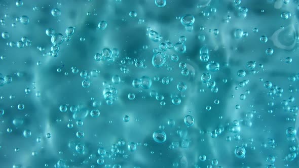 Motion Rotation of the Liquid Gel Fluid Blue Cosmetic Cream Texture with Bubbles alt