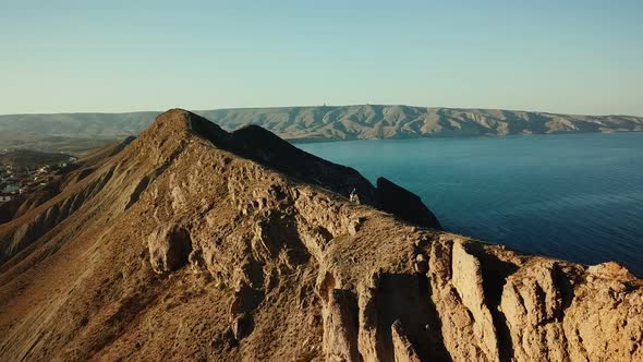 Drone View of Man on Motorbike Extremely Rides Across the Hills with Black Sea on Background in