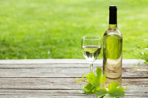 White wine bottle and glass on wooden table Stock Photo by karandaev