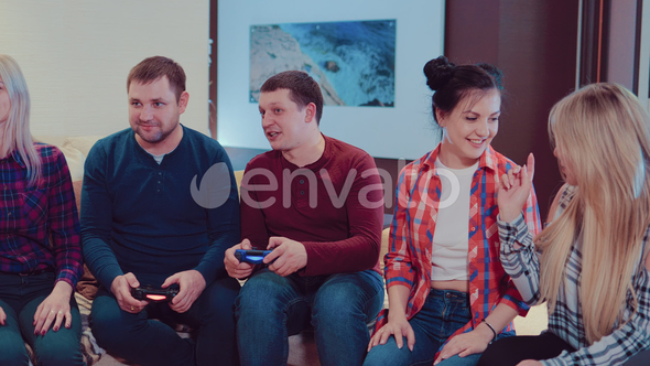 Company of the Friends Enjoy Relaxing on Couch Playing Videogames and Having Fun in Modern Flat alt