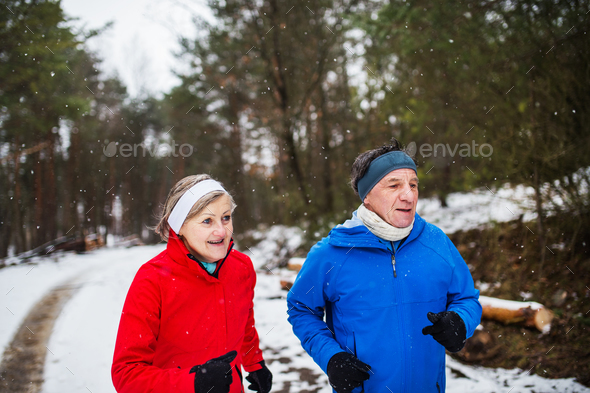 A front view of senior couple jogging in snowy winter nature. Stock Photo by halfpoint