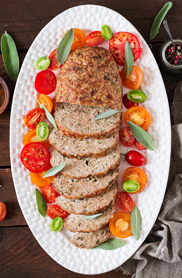 Tasty homemade ground baked turkey meatloaf in white plate on wooden table. Stock Photo by Timolina