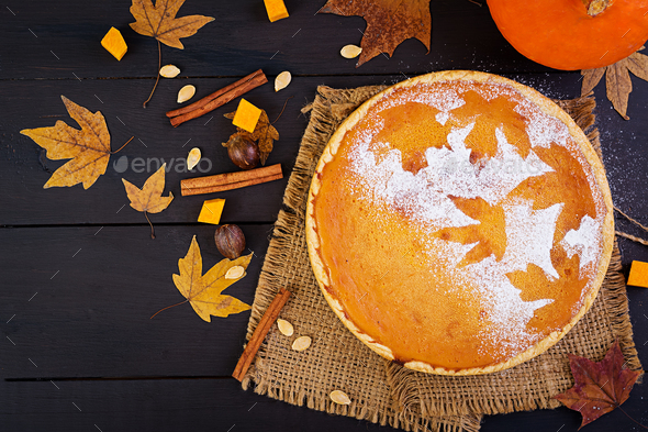 American homemade pumpkin pie with cinnamon and nutmeg, pumpkin seeds and autumn leaves Stock Photo by Timolina