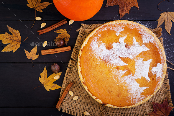 American homemade pumpkin pie with cinnamon and nutmeg, pumpkin seeds and autumn leaves Stock Photo by Timolina