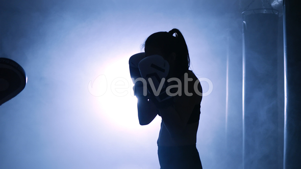 Silhouettes of a Woman Boxer Trains Her Punches on a Punching Bag That Her Partner alt