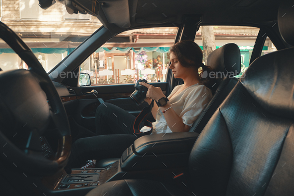 Modern woman tourist, photographer relaxing in the car holding a Stock Photo by arthurhidden