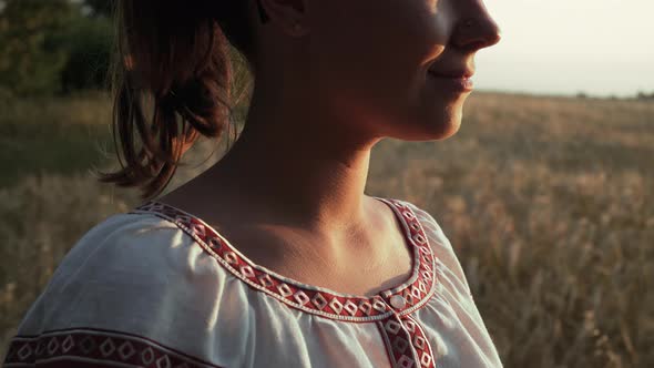 Ukrainian Woman in Vyshyvanka Shirt with Traditional Ornament Standing in Wheat Field alt