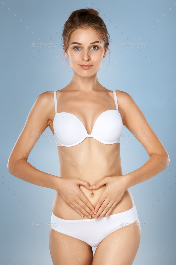 Health issues - female suffering from pain and holding her hands on the stomach - Stock Photo - Images