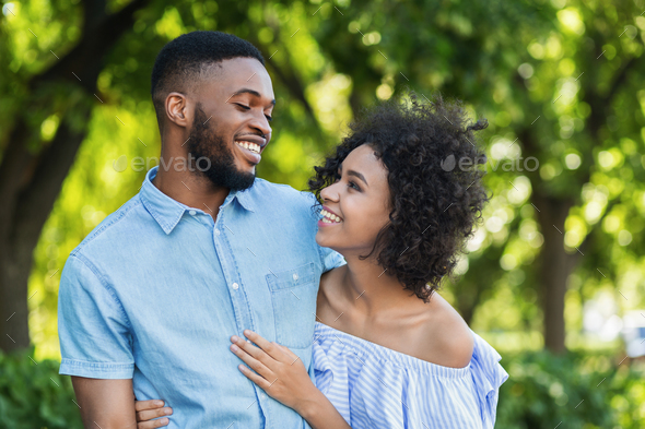 Excited black couple bonding while walking in park Stock Photo by Prostock-studio