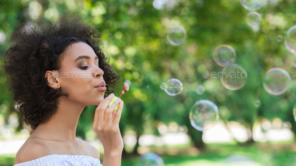 Portrait of young beautiful woman making soap bubbles Stock Photo by Prostock-studio