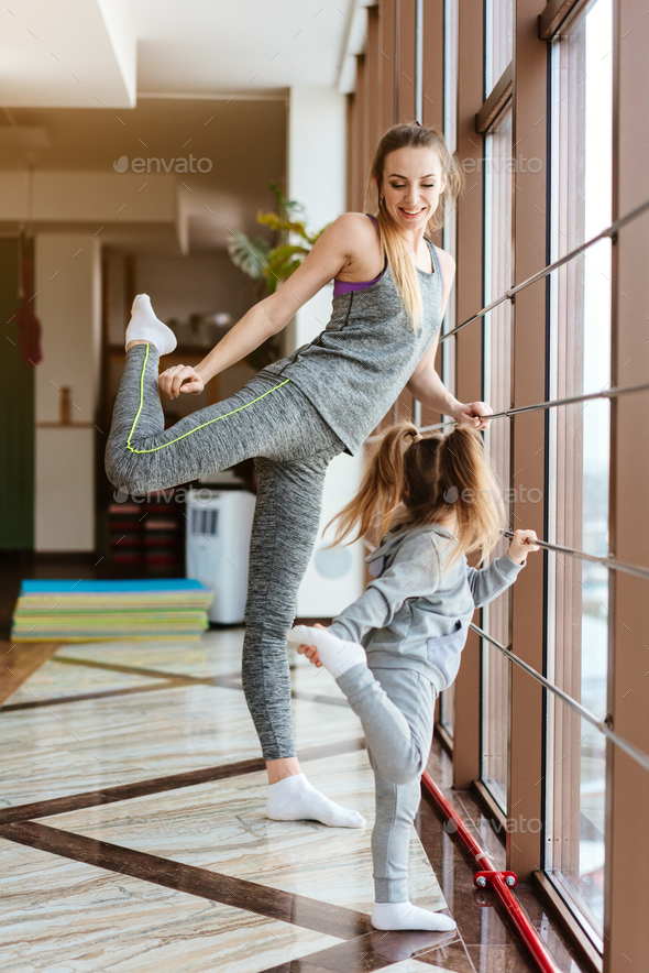 Mom and daughter together perform different exercises Stock Photo by simbiothy