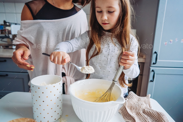 mom teaches her little daughter to cook food Stock Photo by simbiothy