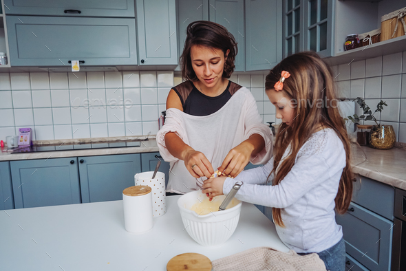 mom teaches her little daughter to cook food Stock Photo by simbiothy