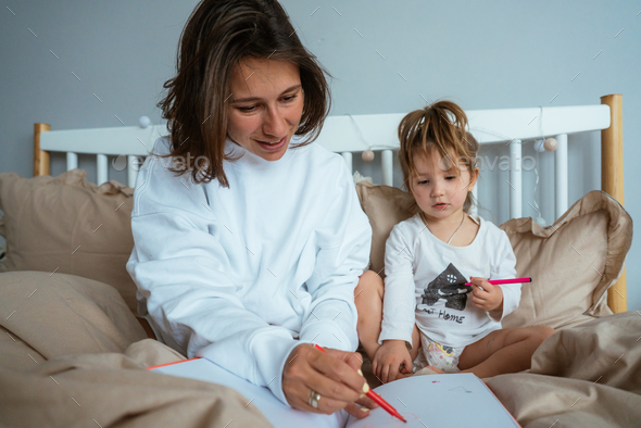 Mom and daughter draw in bed Stock Photo by simbiothy | PhotoDune