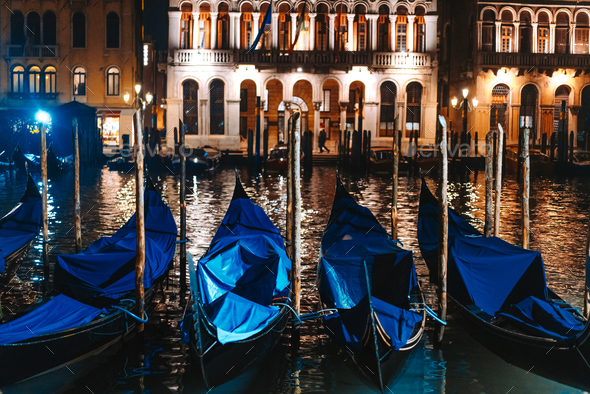 Row of gondolas and glowing streets. Italy, Europe Stock Photo by simbiothy