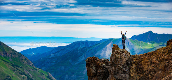 Young Woman Backpacker in Victory Pose with raised up arms on to Stock Photo by kwiktor