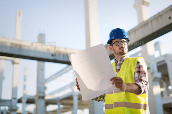 Portrait of male site contractor engineer with hard hat holding blue print paper Stock Photo by nd3000