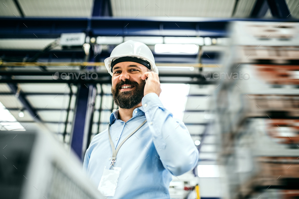 A portrait of an industrial man engineer with smartphone in a factory. Stock Photo by halfpoint