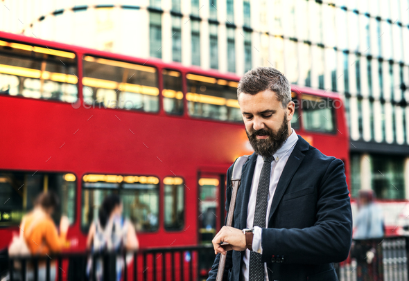 Hipster businessman waiting for the bus in London, checking the time. Stock Photo by halfpoint