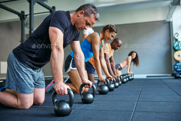 Focused people doing pushups on weights in a gym class Stock Photo by UberImages