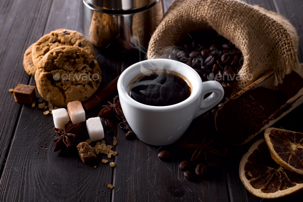ground coffee is filled with a geyser coffee maker and cup of coffee wit spices on a wooden table Stock Photo by lyulkamazur