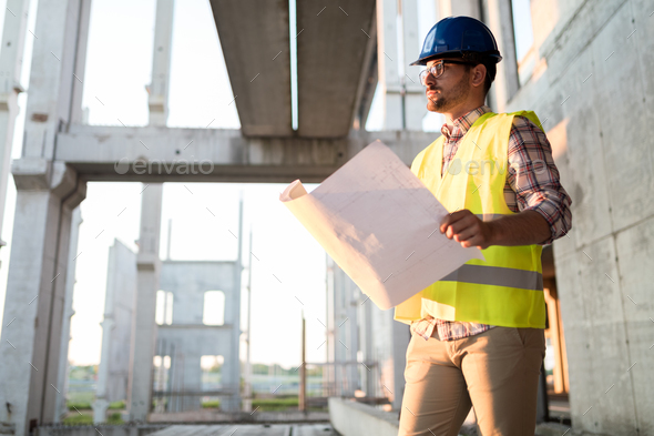 Portrait of male site contractor engineer with hard hat holding blue print paper Stock Photo by nd3000