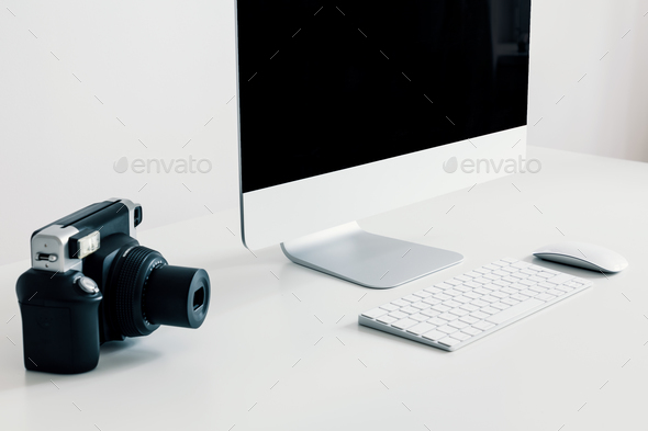 Close-up on camera on white desk with desktop computer and keybo Stock Photo by bialasiewicz