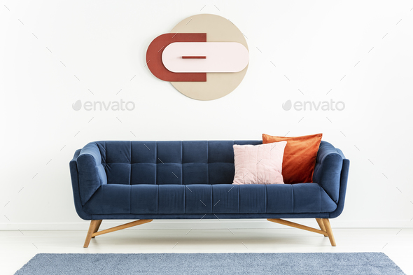 Pink and orange pillows on blue sofa in white apartment interior Stock Photo by bialasiewicz