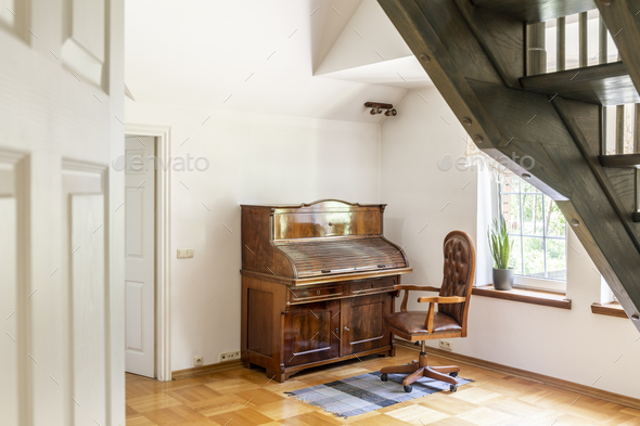 Armchair on rug next to wooden piano in white living room interi