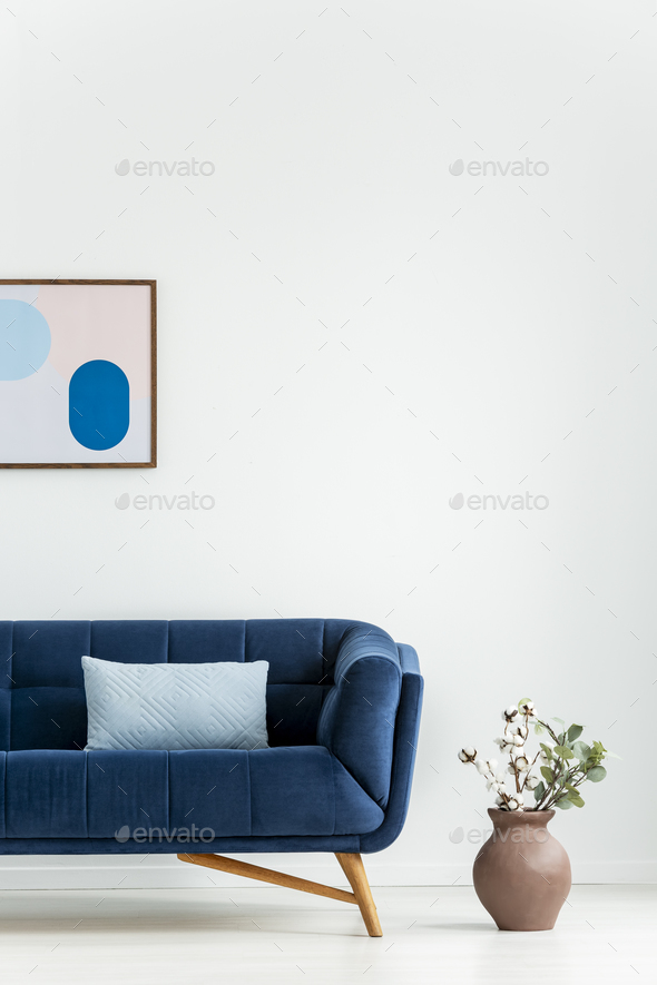 Plant next to navy blue couch with cushion in white living room Stock Photo by bialasiewicz