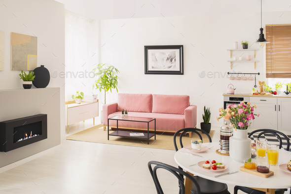 Flowers at table in white apartment interior with poster above p Stock Photo by bialasiewicz