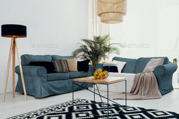 Plant on wooden table near green corner sofa in white living roo Stock Photo by bialasiewicz