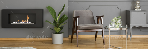 A silver side table and an elegant, upholstered armchair in a mo - Stock Photo - Images