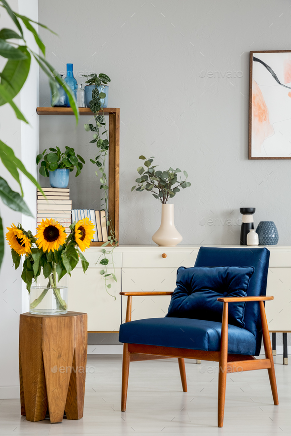 Sunflowers on wooden stool next to blue armchair in living room Sunflowers on wooden stool next to blue armchair in living room
