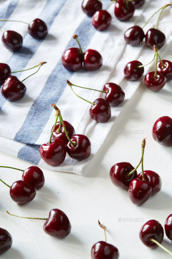 A lot of scattered sweet cherries on the striped table napkin Stock Photo by lenina11only